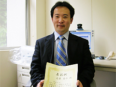 表彰状を手に記念撮影する高原秀介外国語学部講師
