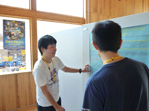神山天文台ボランティアチームの発表ポスターの前で研究会参加者と議論する近本衛さん(法学部2年次生)