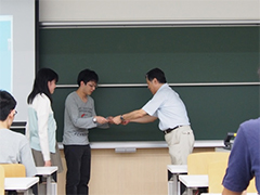 新實治男コンピュータ理工学部教授から賞状が授与された。